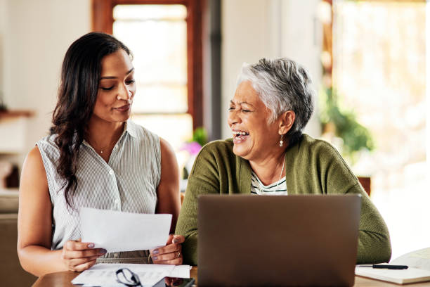 You're doing great with your savings! Cropped shot of a young attractive woman bonding with her grandmother before helping her with her finances in their home pension photos stock pictures, royalty-free photos & images