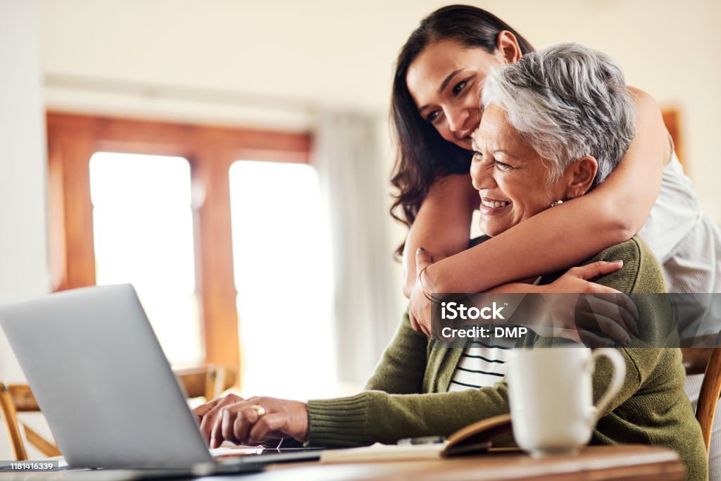 I am always so proud of you Cropped shot of an attractive young woman hugging her grandmother before helping her with her finances on a laptop Senior Adult Stock Photo