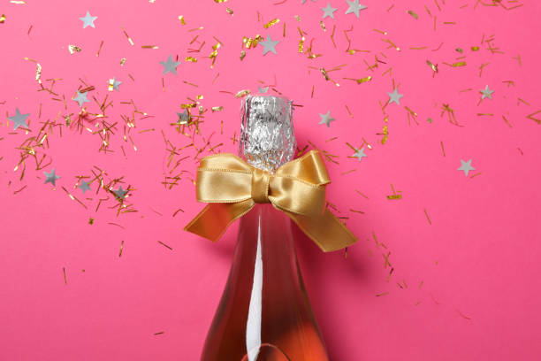 istock Champagne bottle with bow and glitter on pink background, close up 1181417674