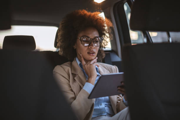 donna d'affari che usa tablet digitale in auto - taxi travel business women foto e immagini stock