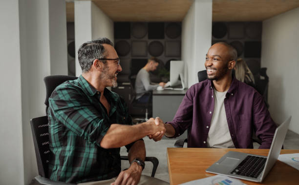 istock Entrepreneurs shaking hands in modern coworking workspace, people working in background 1181423114