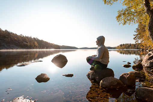A man is taking in the beauty of the nature after an outdoor exercise. He is sitting down to meditate.