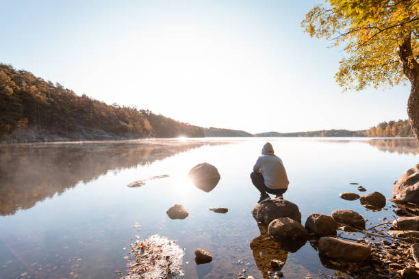 człowiek odpoczywający nad jeziorem po ćwiczeniach na świeżym powietrzu - clear sky reflection sunlight autumn zdjęcia i obrazy z banku zdjęć