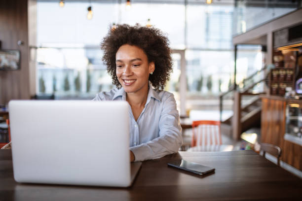 istock Smiling woman using laptop at the bar 1181423296