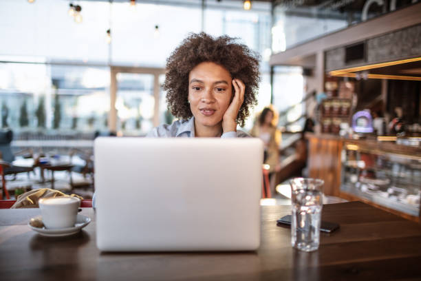 istock Smiling woman using laptop at the bar 1181423346
