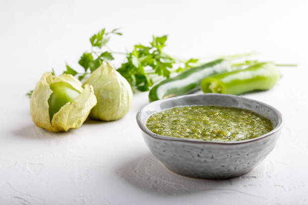 Tomatillo salsa verde. Bowl of spicy green sauce on white table, mexican cuisine. Tomatillo salsa verde. Bowl of spicy green sauce on white table, mexican cuisine. tomatillo photos stock pictures, royalty-free photos & images