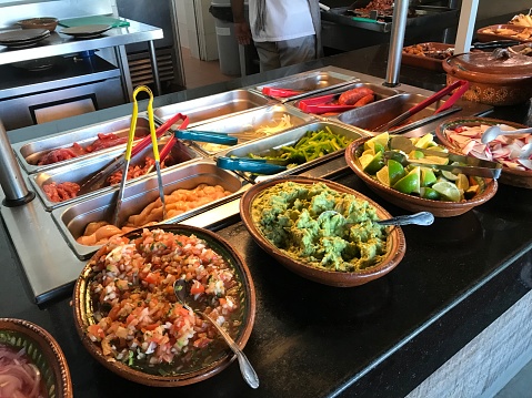 Mexican food display on the buffet with guacamole salsa and lime