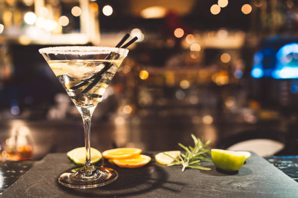 Stylish martini Glass of martini on a grnished surface with lemon slices and rosemary. Black bakground. Glas garnished with sugar on the edge. leather care stock pictures, royalty-free photos & images