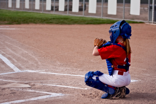 Little girl getting ready to play catcher in a softball game