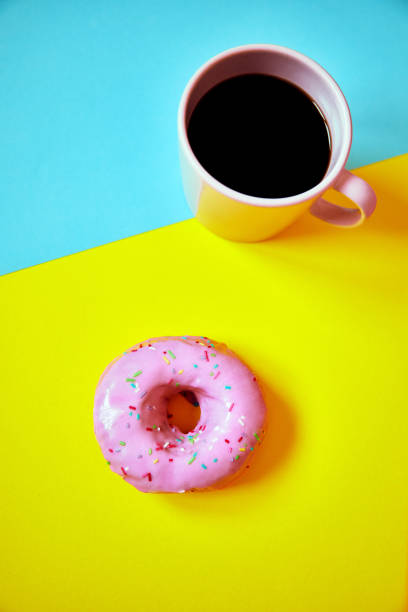 istock Sprinkled donut and cup of coffee on colorful background. 1181430421