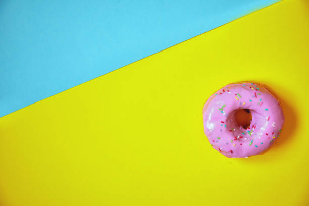 istock Sprinkled pink donut on colorful background. 1181430596