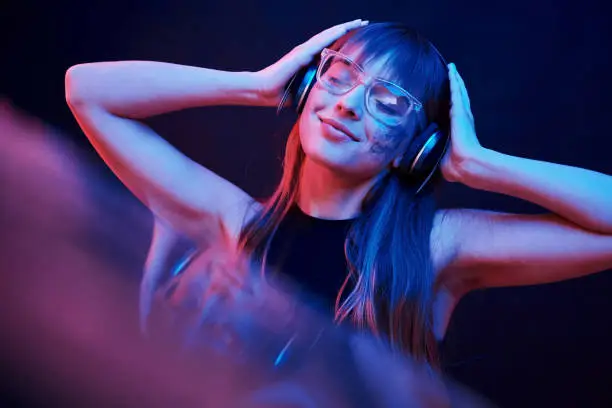 Photo of Stylish glasses. Studio shot in dark studio with neon light. Portrait of young girl