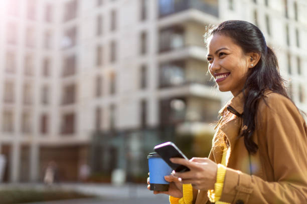 mujer joven con smartphone y café en la ciudad - filipino fotografías e imágenes de stock