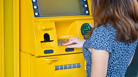 Close-up young woman touching on atm in a shopping mall.