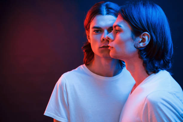 I'm getting double in my eyes. Portrait of twin brothers. Studio shot in dark studio with neon light I'm getting double in my eyes. Portrait of twin brothers. Studio shot in dark studio with neon light. neon portrait boy stock pictures, royalty-free photos & images