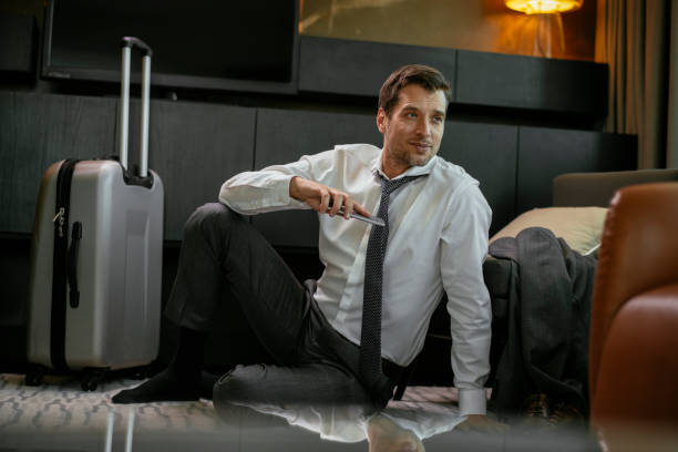 istock Businessman sitting on floor in hotel room 1181442321