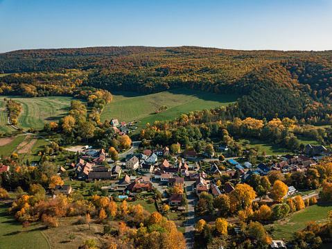 little thuringian village in colorful autumn landscape under blue sunny sky