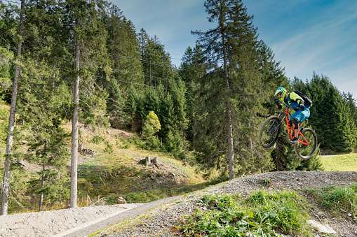 Lenzerheide, GR / Switzerland, - 12 October, 2019: downhill mountain biker jumping high and riding hard in Lenzerheide in the Swiss Alps