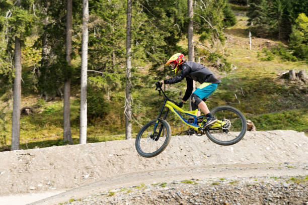 downhill mountain biker jumping high and riding hard in Lenzerheide in the Swiss Alps Lenzerheide, GR / Switzerland, - 12 October, 2019: downhill mountain biker jumping high and riding hard in Lenzerheide in the Swiss Alps elbow pad stock pictures, royalty-free photos & images