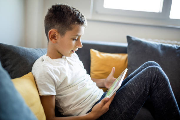 istock Young boy is playing games on his tablet at home 1181443459