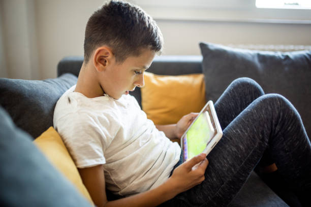 istock Young boy is playing games on his tablet at home 1181443550