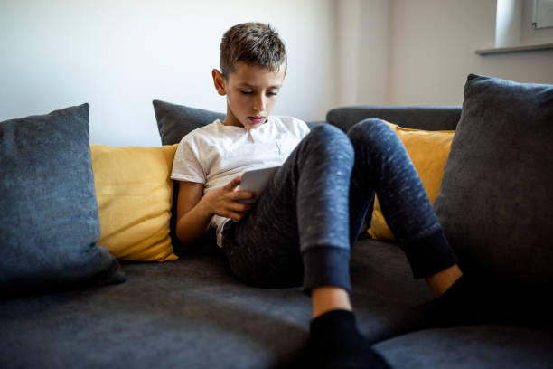 istock Young boy is playing games on his tablet at home 1181443573