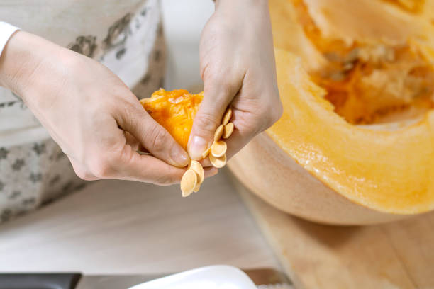 istock Female hands choose fresh pumpkin seeds from fresh orange pumpkin pulp. 1181445209
