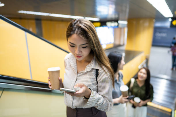 istock Woman drinking coffee and using phone on escalator in the subway 1181446615