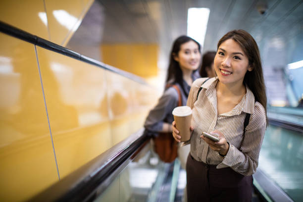 istock Woman drinking coffee and using phone on escalator in the subway 1181446643