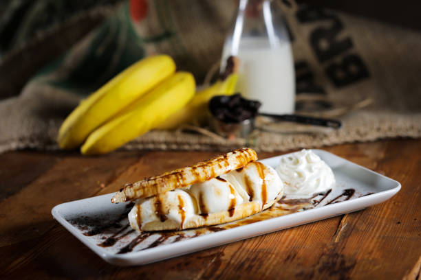 Portion of Banana splits, vanilla ice cream, cream, waffle on a plate outdoors. Close up. Served on Bicycle lane along Drava River in Austria.