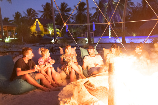 Friends enjoying drinks around the fire pit at a luxury island resort.