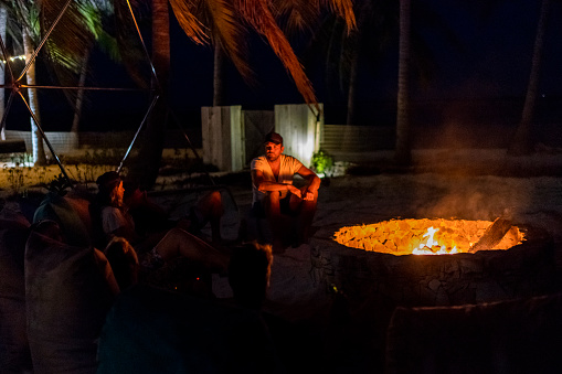 Friends sit around fire pit enjoying island life