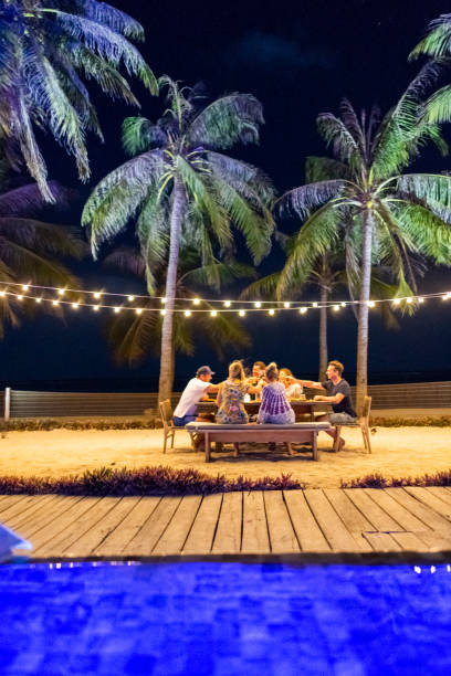 felicidades dos amigos! apreciando o partido de jantar confidencial na praia - tourist resort hotel swimming pool night - fotografias e filmes do acervo