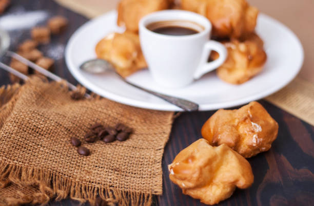 istock Cup of hot black coffee with home made profiteroles on a rustic table 1181456135