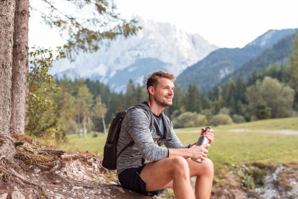 istock Young man sitting and resting in mountains 1181461933