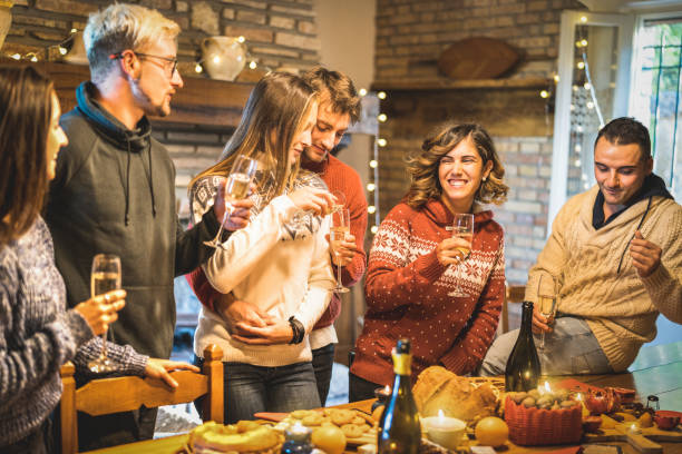 夕食の夕食に白ワインと甘い食べ物でクリスマスパーティーを祝う幸せな友人グループ - 若者が時間を楽しみ、一緒に食べる楽しみを持つ冬の休日の概念 - 暖かいフィルタ - apres ski party winter cabin ストックフォトと画像