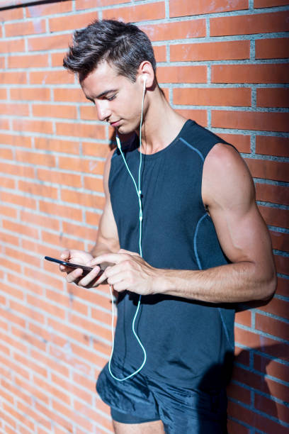 istock Young sports man next to a brick wall using a smartphone 1181463442