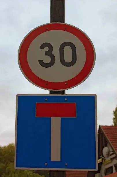 Two road signs on post against cloudy sky represent speed limit and deadlock sign. Balatonfoldvar, Hungary. Concept of road sign.