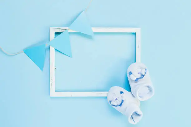 Photo of Newborn flat lay postcard. Baby booties shoes for boy and girl on a blue pink background. Congratulations on the birth of a newborn baby with copy space.