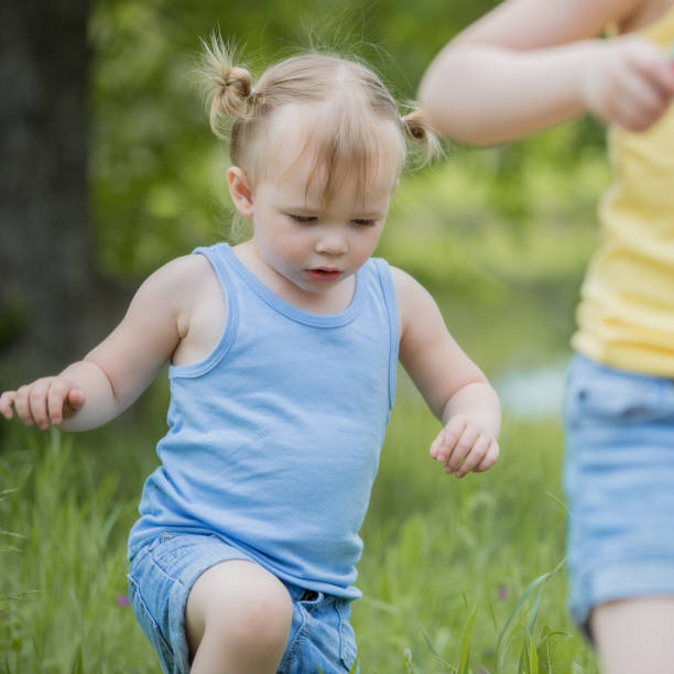istock Toddler walking with sister through tall grass 1181471725