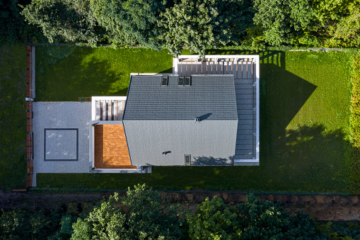 Aerial view from drone of modern house with green lawn surrounded by trees