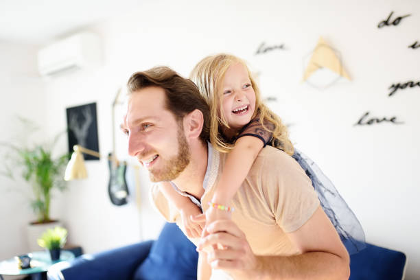 happy young handsome father with his little curly hair daughter playing at home. - blond hair carrying little girls small imagens e fotografias de stock