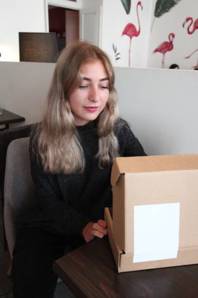 istock A young girl sits in a cafe and looks inside an open box. 1181477785