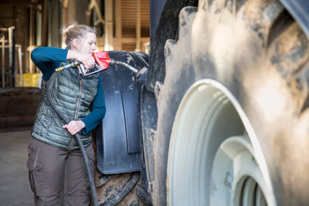 mujer agricultor a repostar el tractor en la estación de servicio - foto de stock