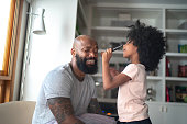 Daughter doing makeup to shy father at home