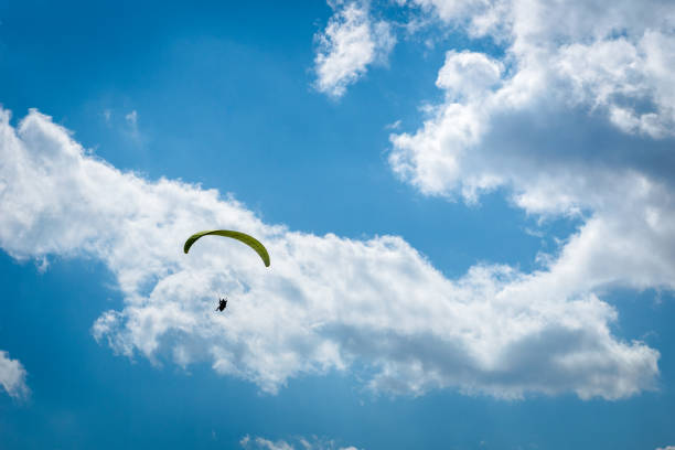 istock paraglider paragliding over blue sky with white clouds 1181484154