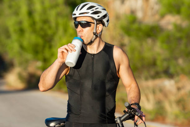 istock male cyclist resting and drinking isotonic drink 1181484521