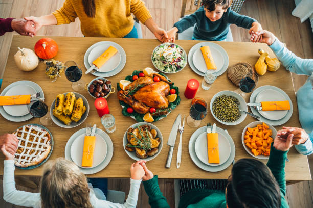 istock Family praying over Thanksgiving day table 1181484614