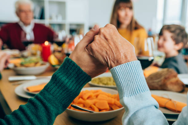 Family prayer Close-up shot of a people holding hands in prayer before having a holiday dinner or lunch. saying grace stock pictures, royalty-free photos & images