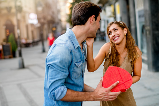 Cheerful young woman receiving a gift from her boyfriend